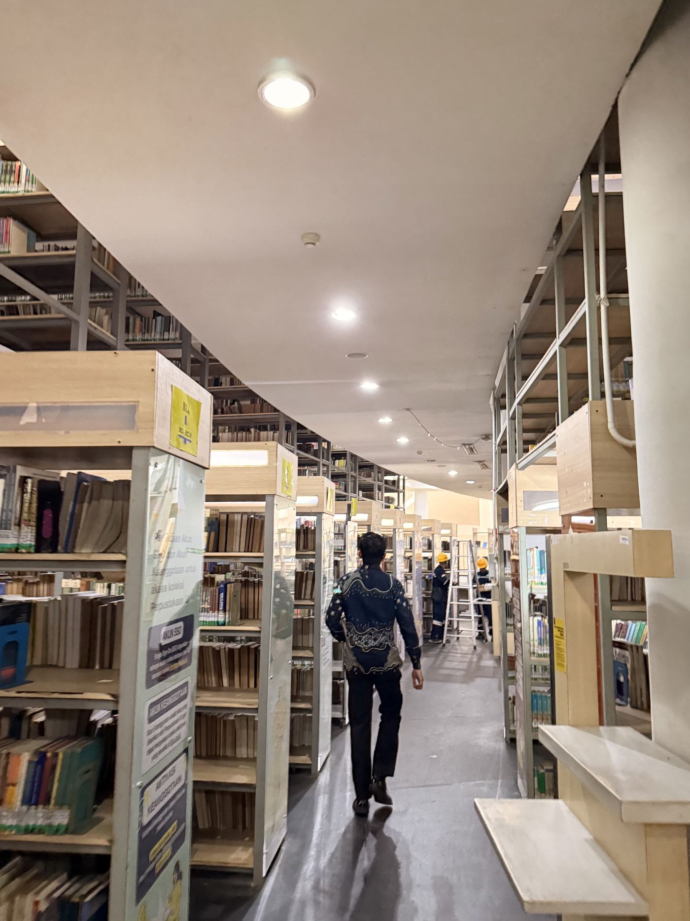 Dr. (Cand.) Putu George Matthew Simbolon, S.H., M.H. walking through the law library stacks at Universitas Indonesia