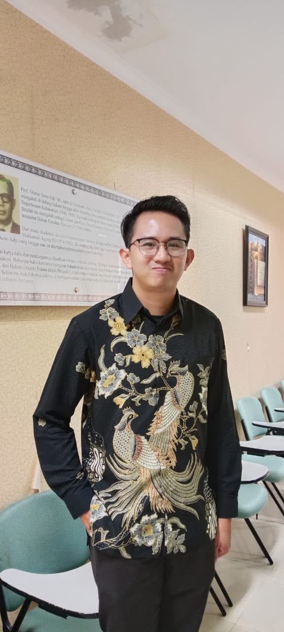 Dr. (Cand.) Putu George Matthew Simbolon, S.H., M.H. in batik in a seminar room